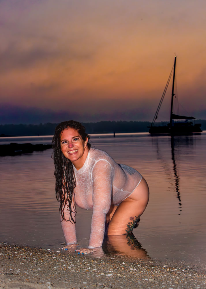 Woman crawling gout of water laughing at sunrise