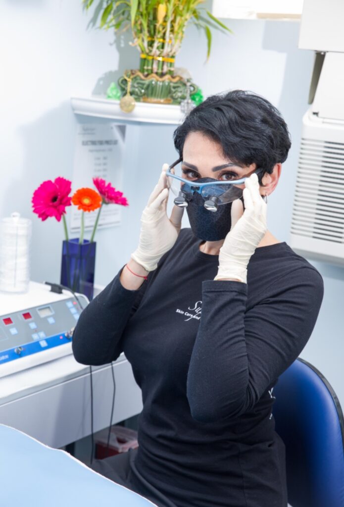 The clinician wearing protective eyewear, gloves, and a mask in preparation for her client's permanent hair removal