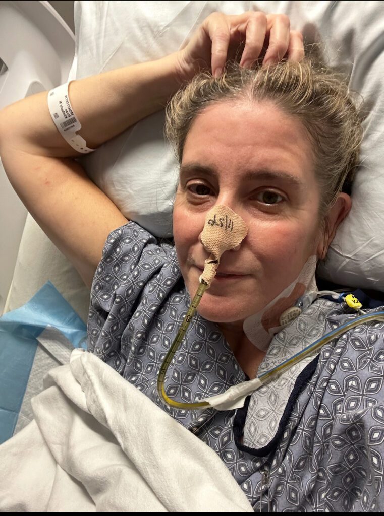 portrait of a women laying in a hospital bed with a gtube in her nose to help feed her