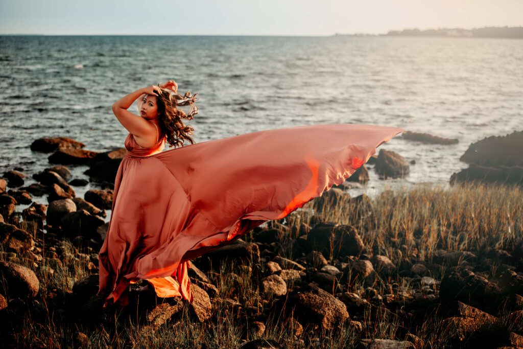 woman on rocky beach wearing a flying dress in south shore massachusetts